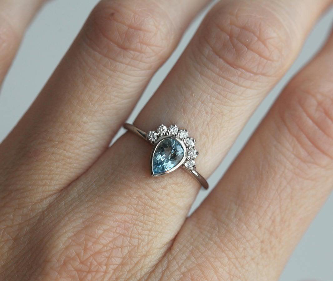 Birnenförmiger Aquamarinring mit runden weißen Diamanten, die einen Heiligenschein bilden