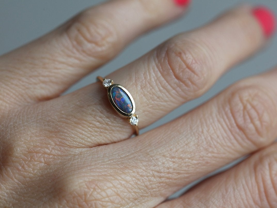 Ovaler Ring aus drei Steinen mit schwarzem Opal und zwei seitlichen weißen Diamanten