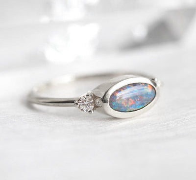 Ovaler Ring aus drei Steinen mit schwarzem Opal und zwei seitlichen weißen Diamanten