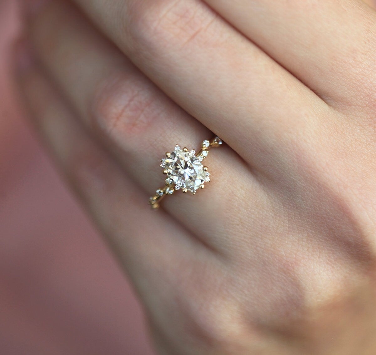 Ovaler Clusterring mit weißen Diamanten und seitlichen weißen runden Diamanten, die wie eine Ranke zum Mittelstein hin angeordnet sind