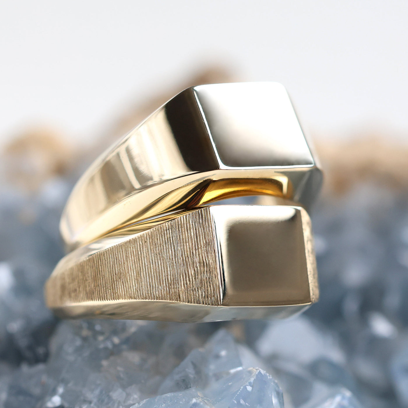 Eine Nahaufnahme eines goldenen Siegelrings auf einem Felsen, der hochwertige Metalle wie Sterlingsilber, massives Gold und Platin zeigt. Personalisierbar mit Edelsteinen.