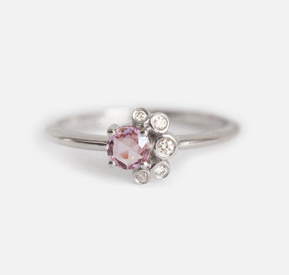 Nahaufnahme eines runden Saphir-Diamant-Clusterrings mit rosa Saphir und weißen Diamanten.