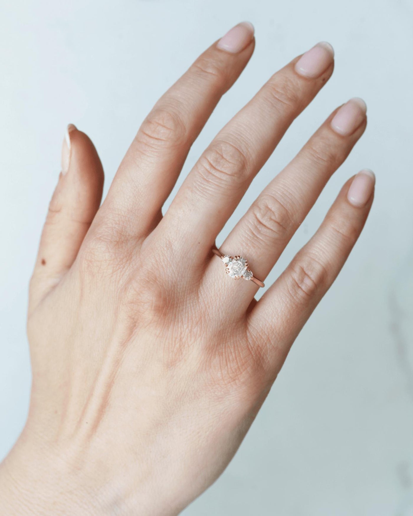 Ein Verlobungsring aus 14 Karat Gelbgold mit einem Mittelstein aus weißem Diamant im Kissenschliff und zwei runden Akzentsteinen aus weißem Diamant auf beiden Seiten