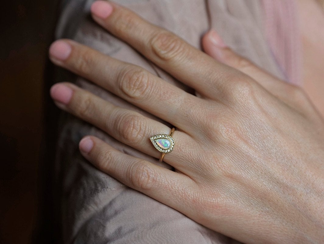 Weißer Birnen-Opal-Halo-Ring aus Gelbgold mit runden weißen Diamanten, die den Hauptedelstein umgeben