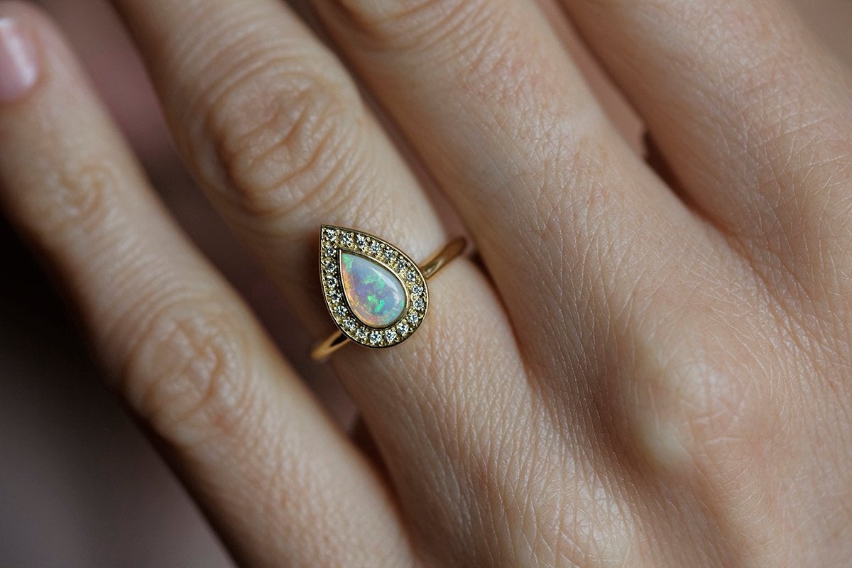 Weißer Birnen-Opal-Halo-Ring aus Gelbgold mit runden weißen Diamanten, die den Hauptedelstein umgeben