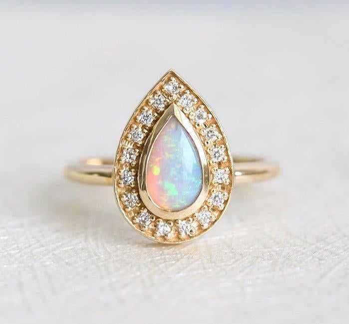 Weißer Birnen-Opal-Halo-Ring aus Gelbgold mit runden weißen Diamanten, die den Hauptedelstein umgeben