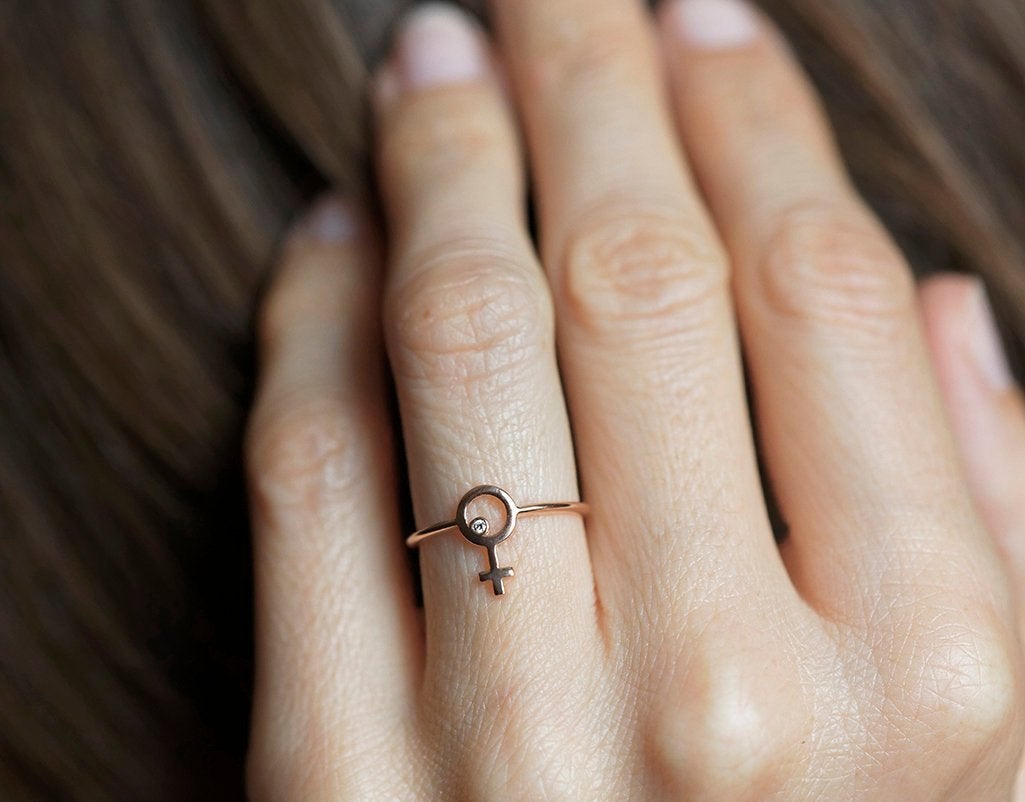 Ring aus Roségold mit einem kleinen runden Diamanten in der Mitte eines weiblichen Symbols