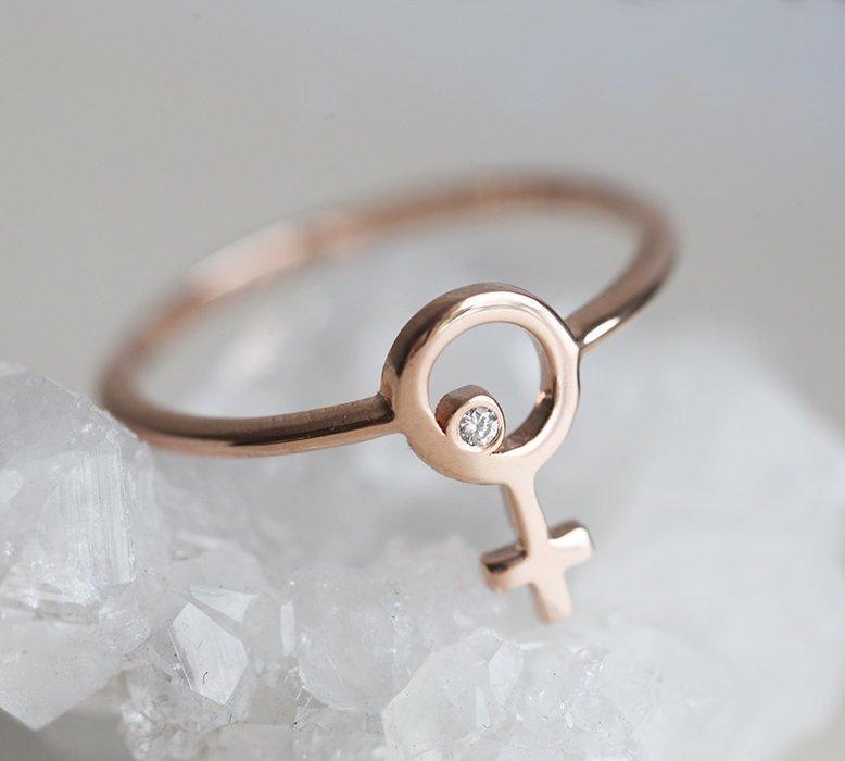 Ring aus Roségold mit einem kleinen runden Diamanten in der Mitte eines weiblichen Symbols