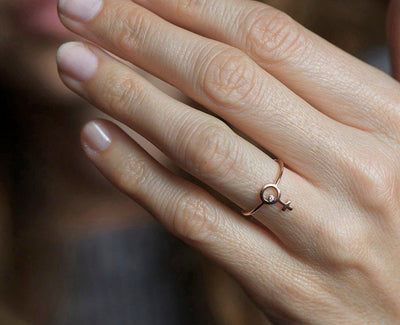 Ring aus Roségold mit einem kleinen runden Diamanten in der Mitte eines weiblichen Symbols