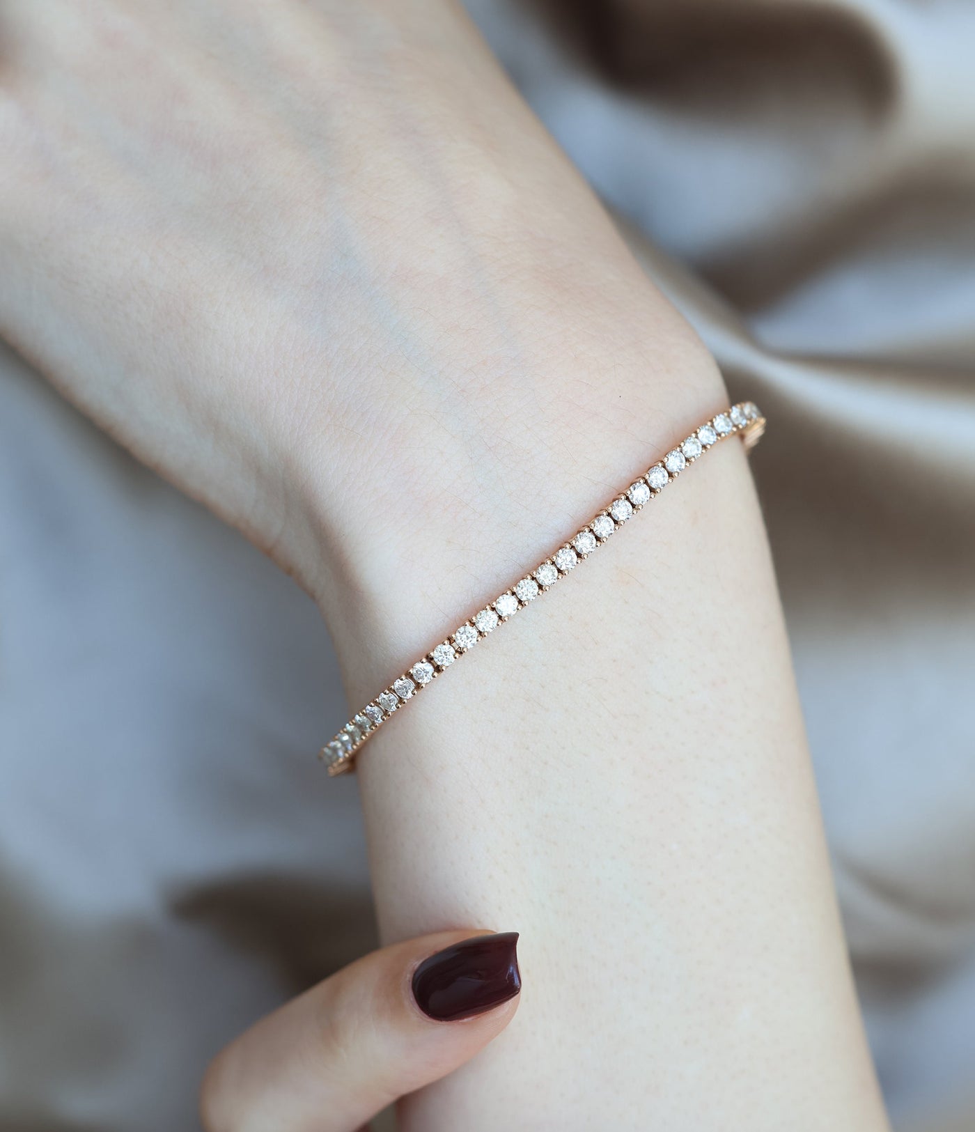 Person, die ein Diamant-Tennisarmband aus 18 Karat Roségold trägt.