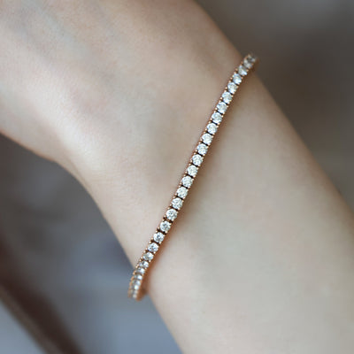 Person, die ein Diamant-Tennisarmband aus 18 Karat Roségold trägt.