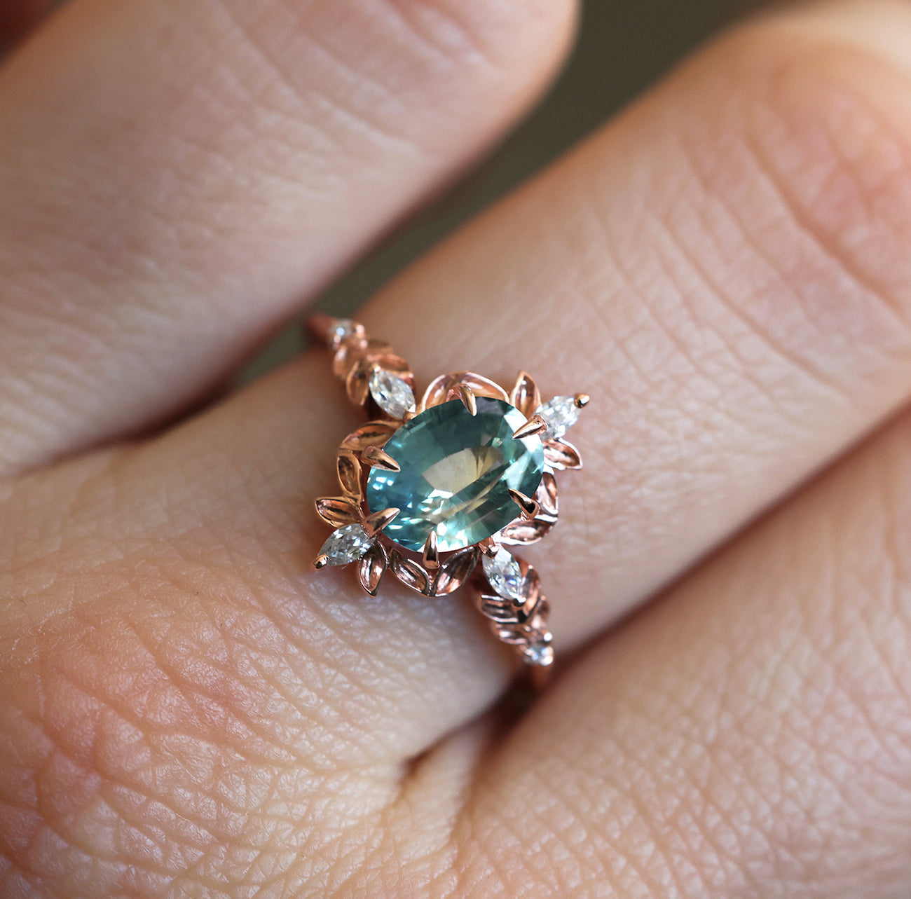 Ovaler Verlobungsring mit blauem Saphir und weißen Marquise-Diamanten an einer Hand.