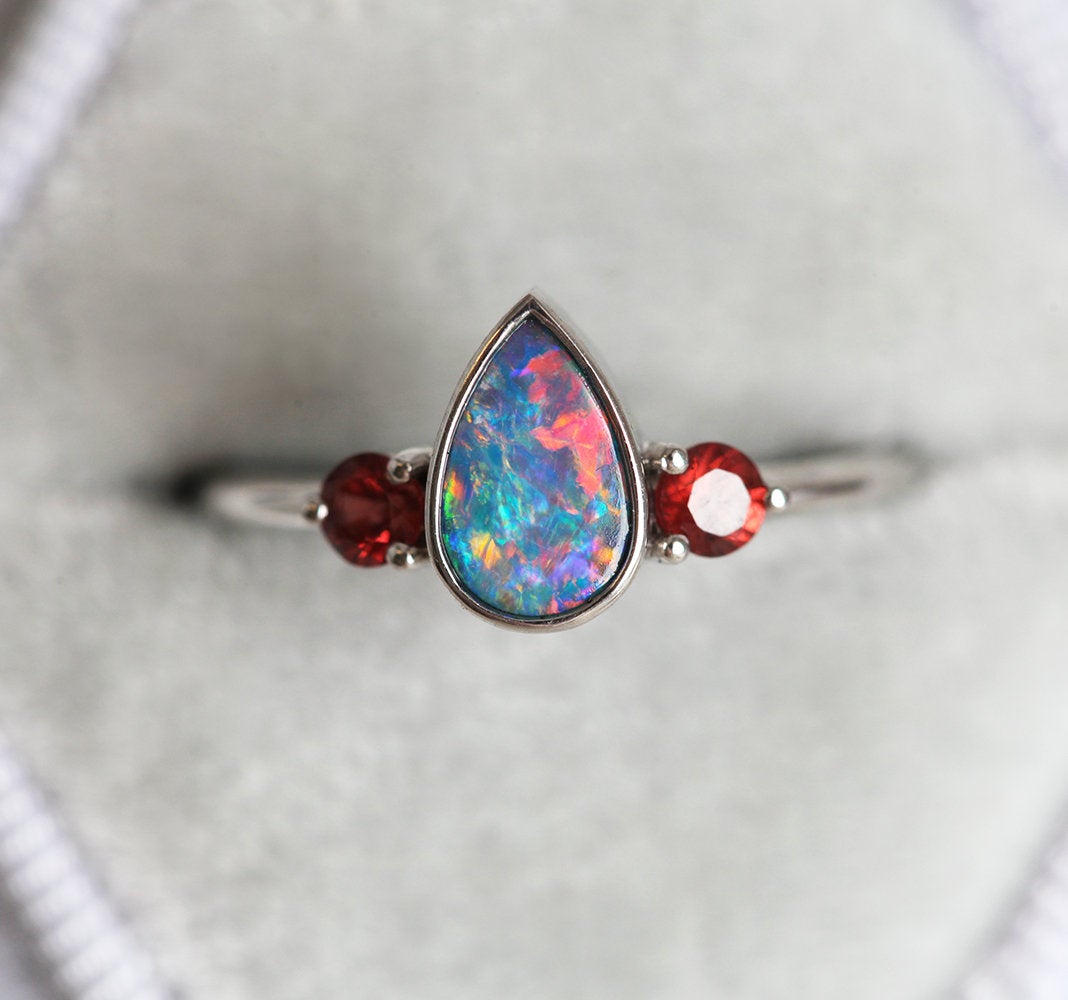 Drei-Stein-Ring mit schwarzem Birnen-Australier-Opal und akzentuierten roten runden Granat-Edelsteinen