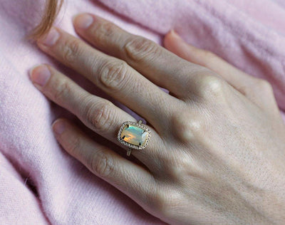 Opal-Halo-Ring im Kissenschliff mit seitlichen runden weißen Diamanten und Diamanten entlang des Bandes