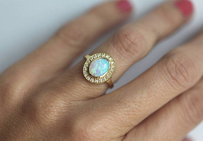 Ovaler Opal-Halo-Ring aus Gelbgold mit seitlichen weißen runden Diamanten