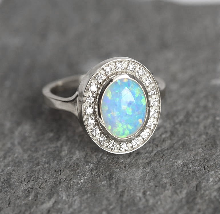 Ovaler Opal-Halo-Ring aus Weißgold mit seitlichen weißen runden Diamanten