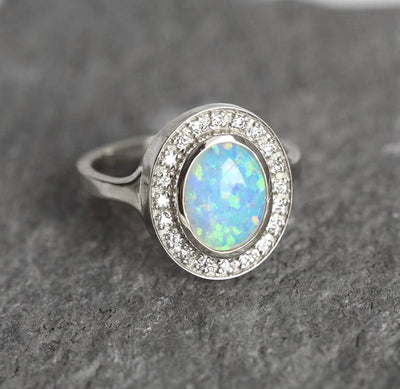 Ovaler Opal-Halo-Ring aus Weißgold mit seitlichen weißen runden Diamanten