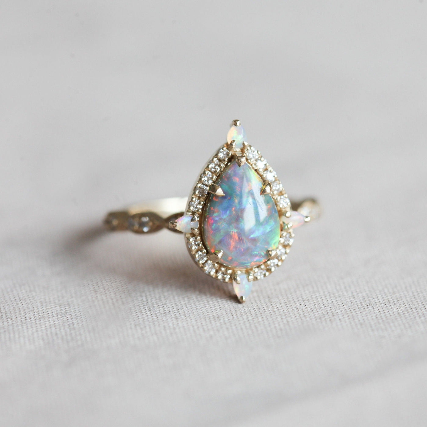 Birnen-Opal-Halo-Ring mit seitlichen runden weißen Diamanten und Birnen-Opalen