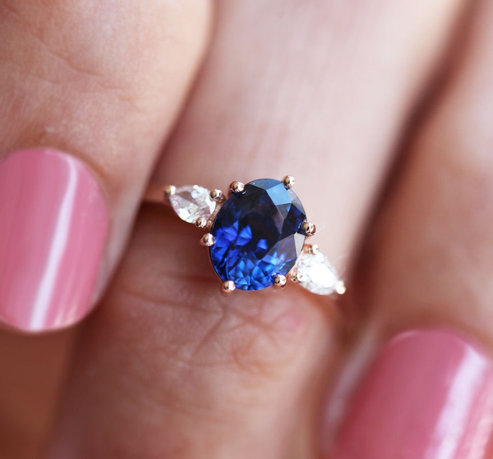 Ovaler blauer Saphirring mit weißen Diamanten an der Seite