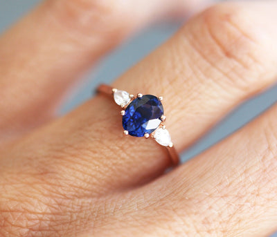 Ovaler blauer Saphirring mit weißen Diamanten an der Seite