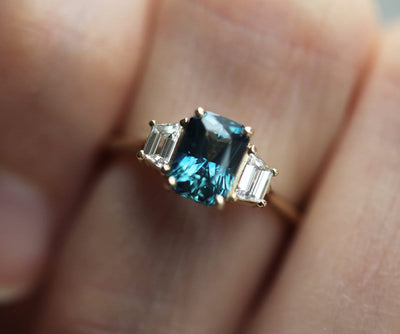 Blauer Saphirring im Smaragdschliff mit weißen Diamanten an der Seite