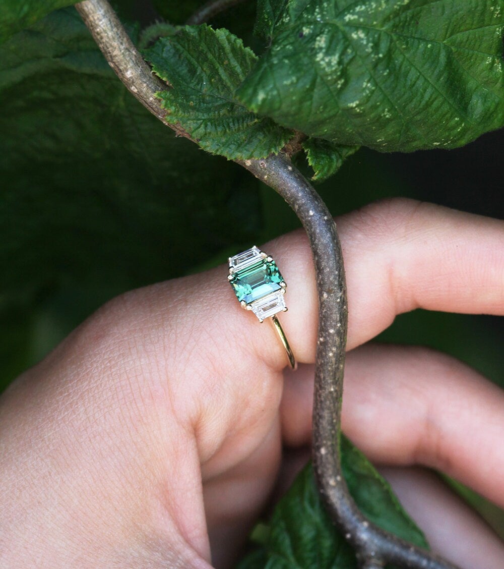 Blauer Saphirring im Smaragdschliff mit weißen Diamanten an der Seite