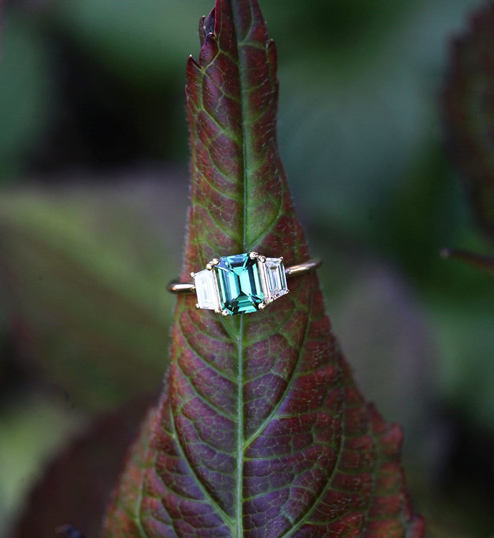 Blauer Saphirring im Smaragdschliff mit weißen Diamanten an der Seite