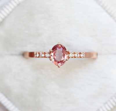 Ovaler pfirsichfarbener Padparadscha-Saphirring mit weißen Diamanten an der Seite