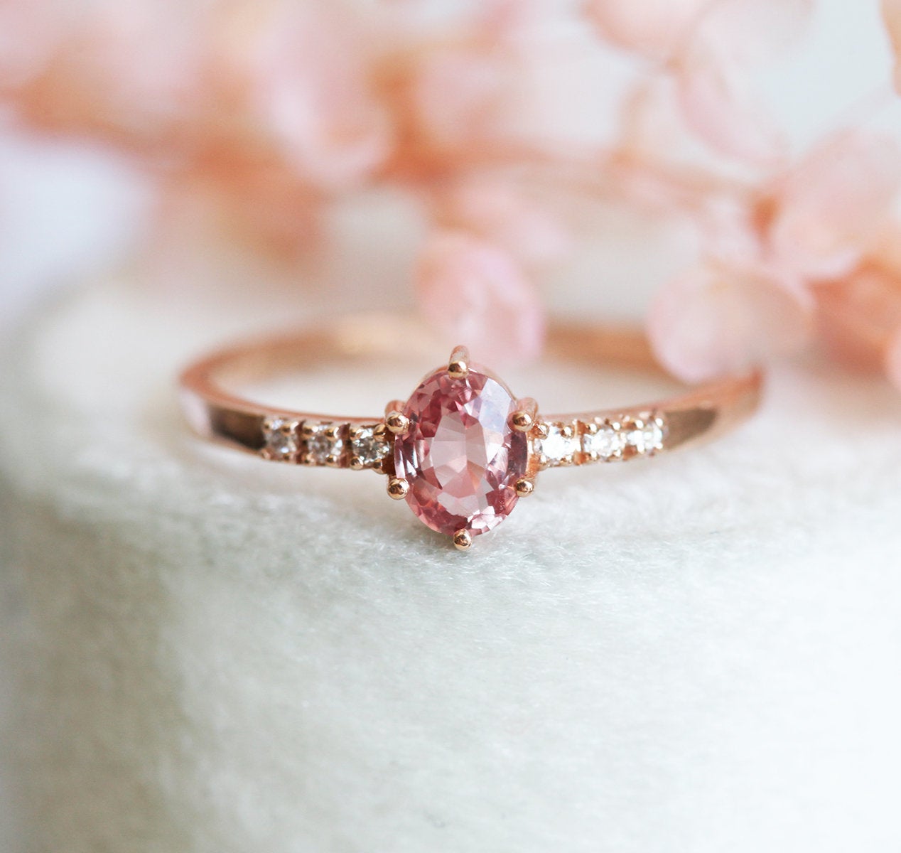 Ovaler pfirsichfarbener Padparadscha-Saphirring mit weißen Diamanten an der Seite