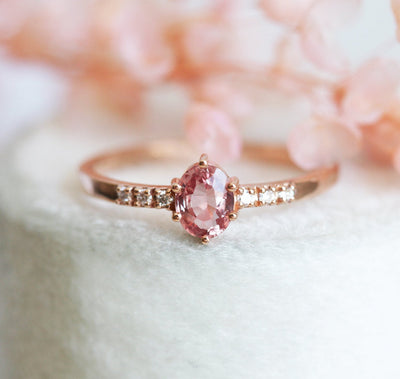 Ovaler pfirsichfarbener Padparadscha-Saphirring mit weißen Diamanten an der Seite