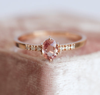 Ovaler pfirsichfarbener Padparadscha-Saphirring mit weißen Diamanten an der Seite