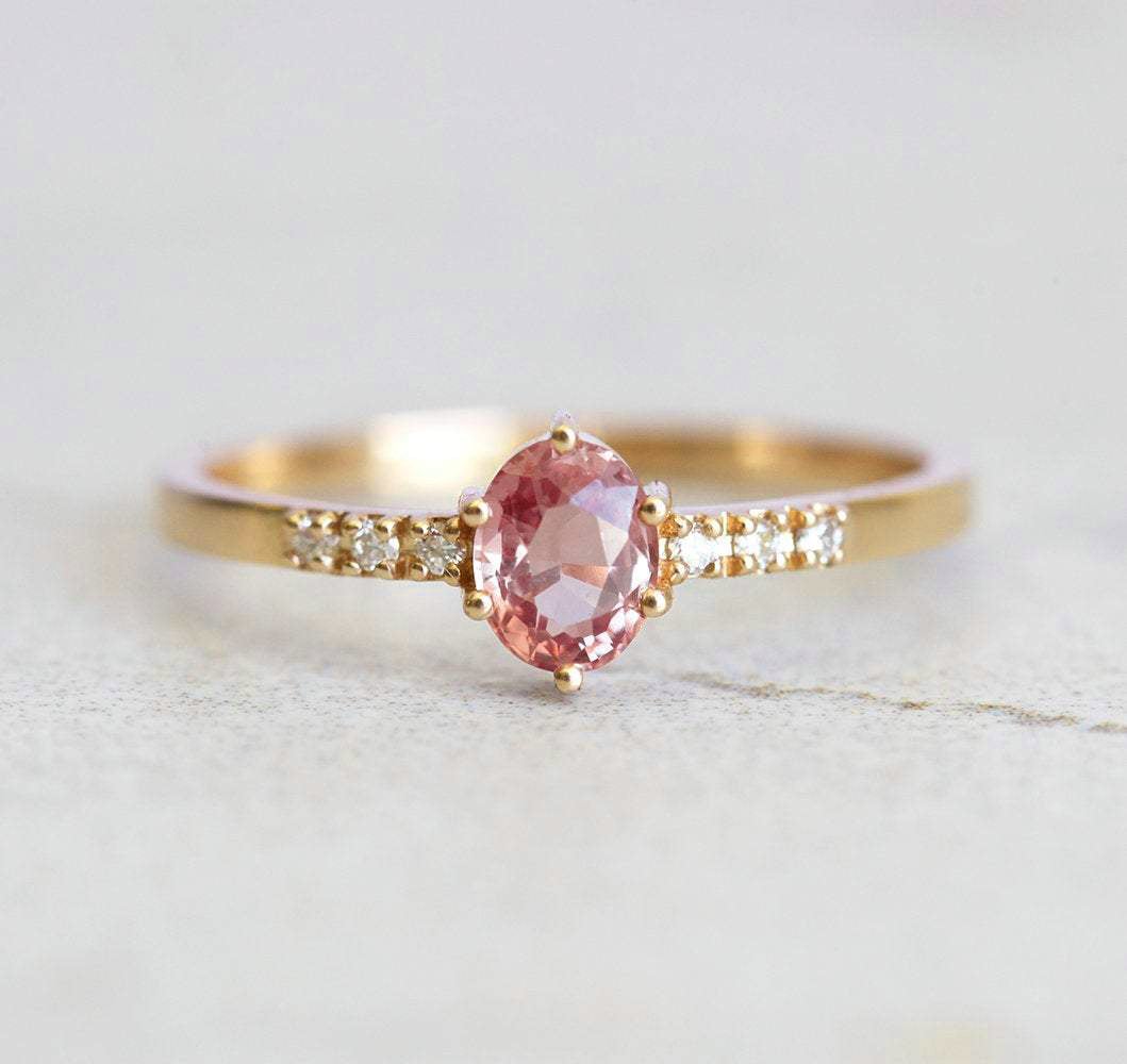 Ovaler pfirsichfarbener Padparadscha-Saphirring mit weißen Diamanten an der Seite