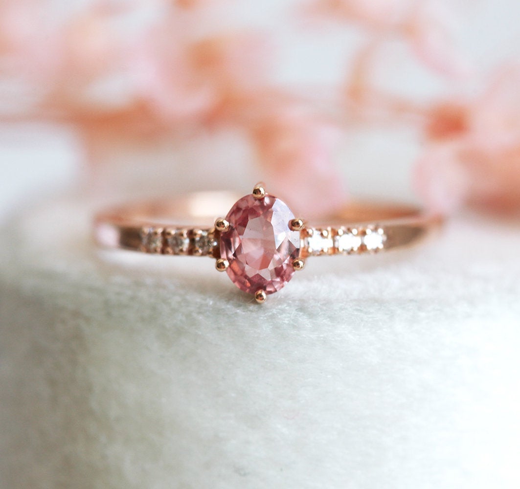 Ovaler pfirsichfarbener Padparadscha-Saphirring mit weißen Diamanten an der Seite