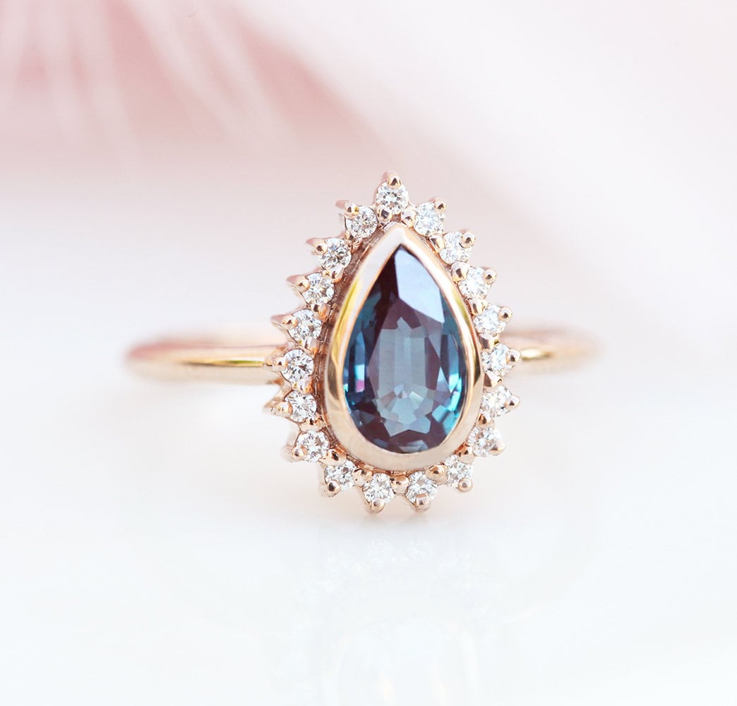 Blauer Birnen-Alexandrit-Ring mit vielen kleineren weißen Diamanten an der Seite